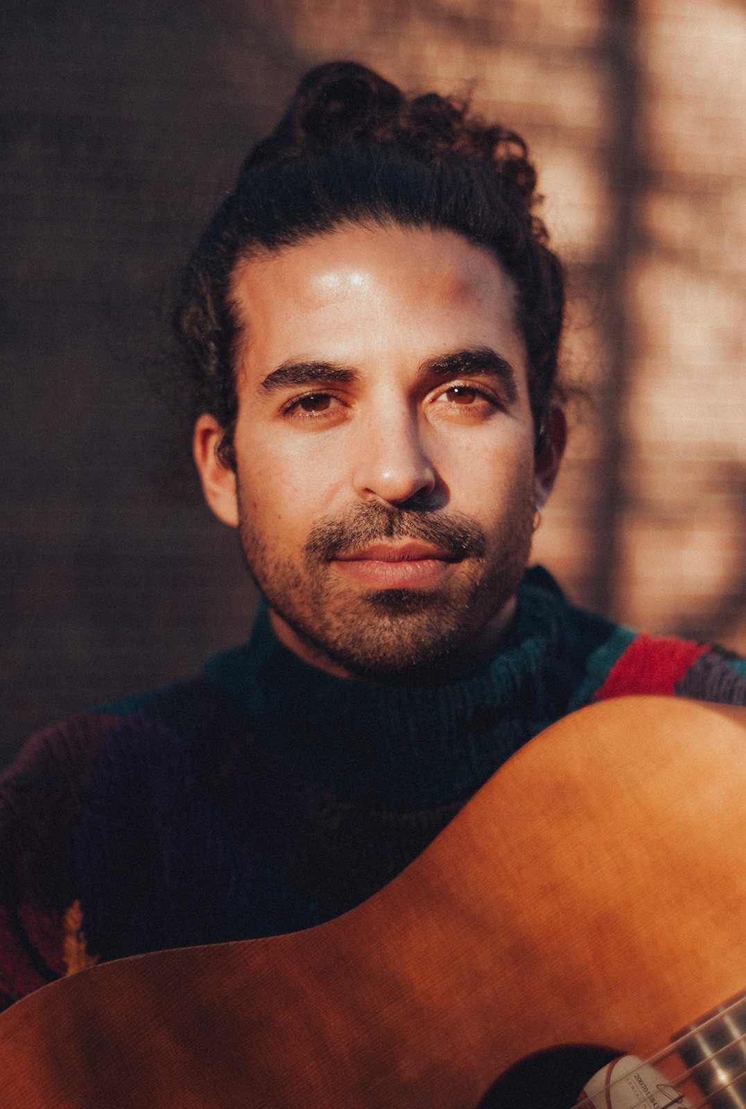 Kai Gluska with acoustic guitar in warm evening light